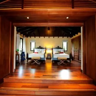 Royal Isabela Hotel Amenities photo This is an image of a luxurious and spacious hotel room or suite, viewed from the doorway.

The room features a warm, inviting atmosphere, characterized by rich, dark wooden accents. The doorway itself is framed by heavy, polished wood, leading into 