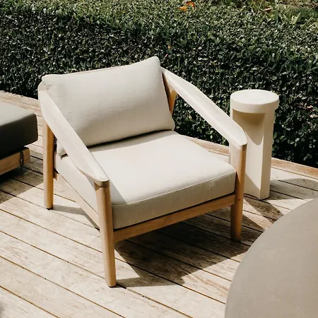 Royal Isabela Hotel Exterior photo This is a photo featuring an elegant outdoor armchair situated on a wooden deck, set against a backdrop of lush green hedging.

**Key elements in the image:**

*   **Armchair:** The central focus is a modern, low-profile armchair with a light-colored